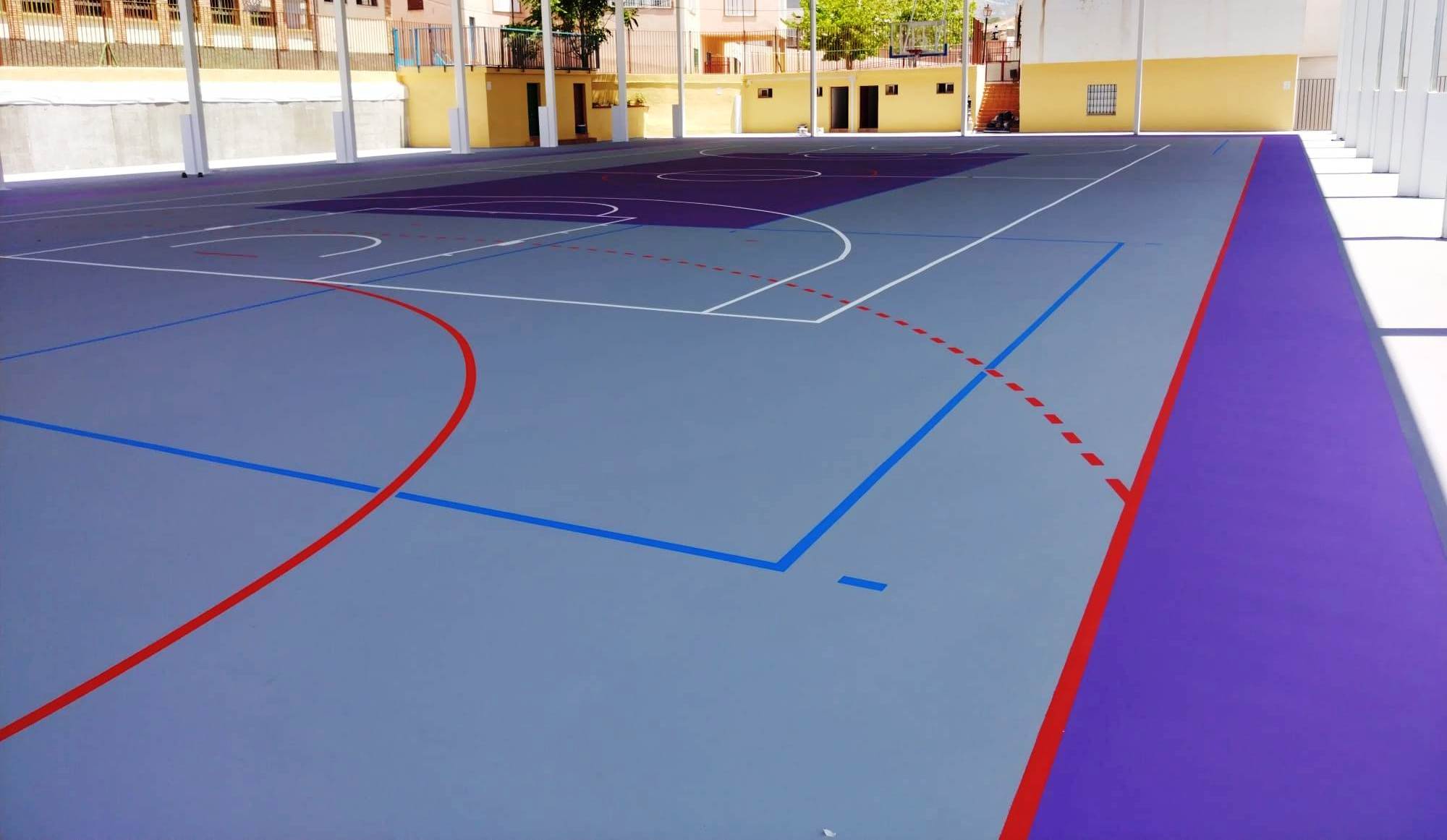 Cancha de deportes múltiples con superficie de color gris y líneas de demarcación para diferentes juegos.