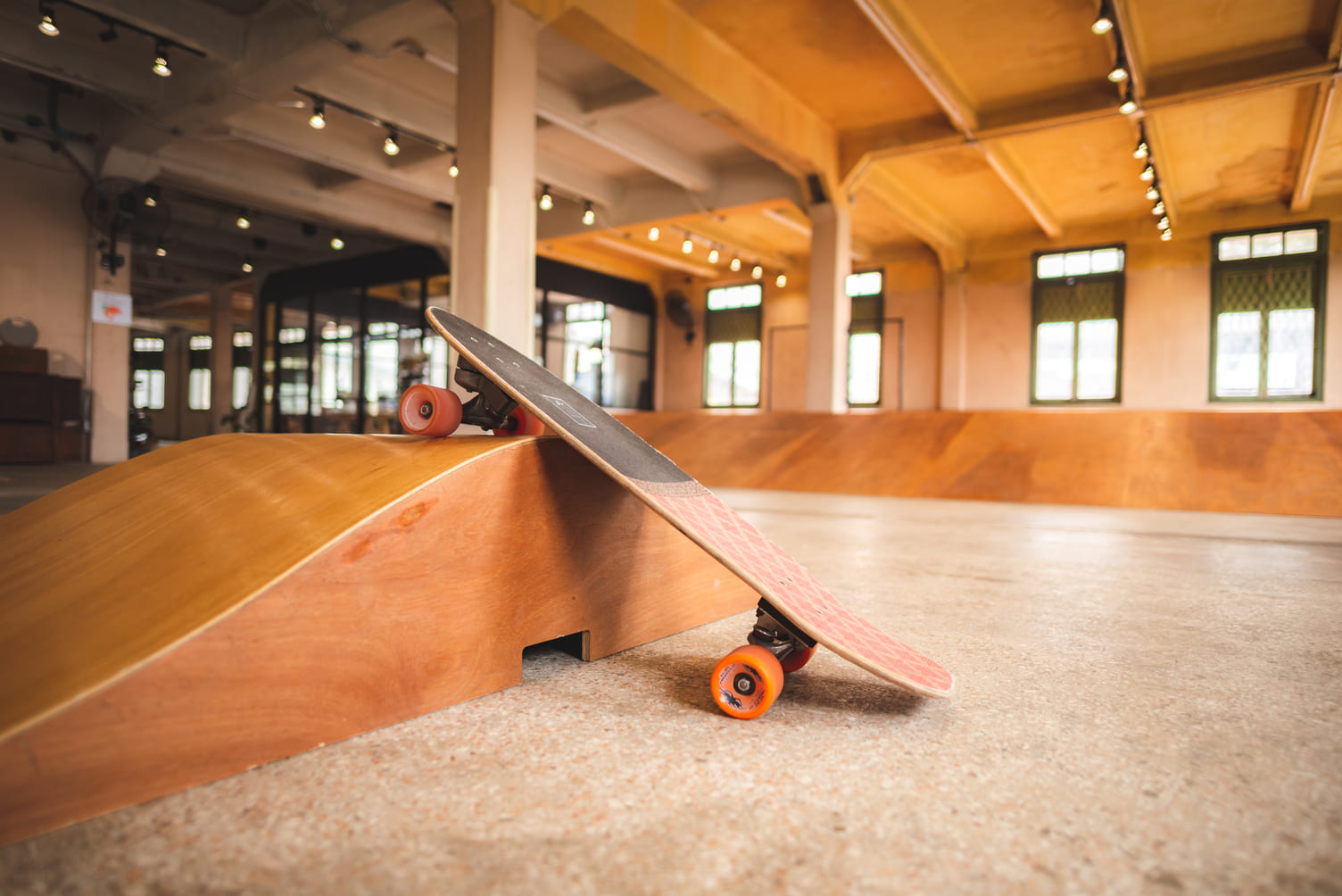 Skateboard en una rampa de madera en un skatepark interior.