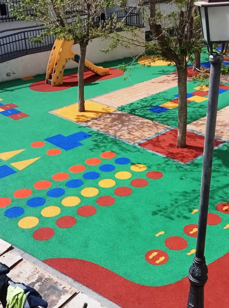 Parque infantil con suelo de caucho colorido y juegos didácticos.